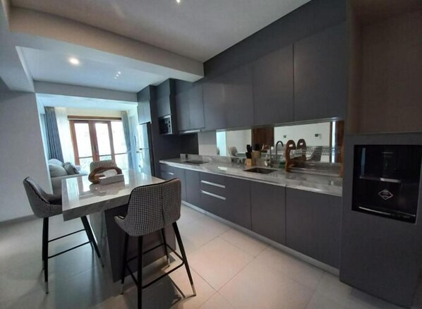 Une cuisine moderne avec des meubles de couleur sombre, un îlot central et des tabourets de bar.