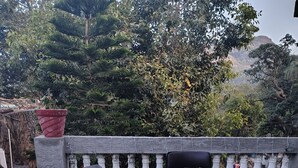 A terrace with black metal chairs and round wooden tables, surrounded by a white balustrade.