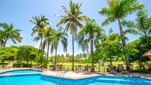 A swimming pool surrounded by palm trees and lounge chairs.