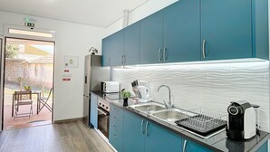 A modern kitchen with teal cabinets, stainless steel appliances, and a black countertop. - Gomes House by Atlantic Holiday (Ponta do Sol)