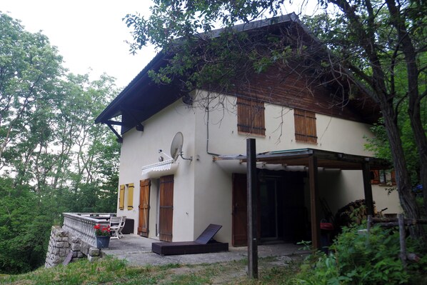 A two-story house with a covered porch, a stone wall, and a wooden door.