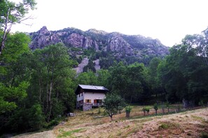 A house with a stone foundation, a wooden deck, and a mountain backdrop.