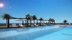 Une piscine entourée de palmiers, avec des chaises longues et des parasols.