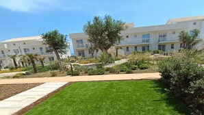 Une pelouse bien entretenue, avec un chemin menant à un bâtiment doté de plusieurs balcons.