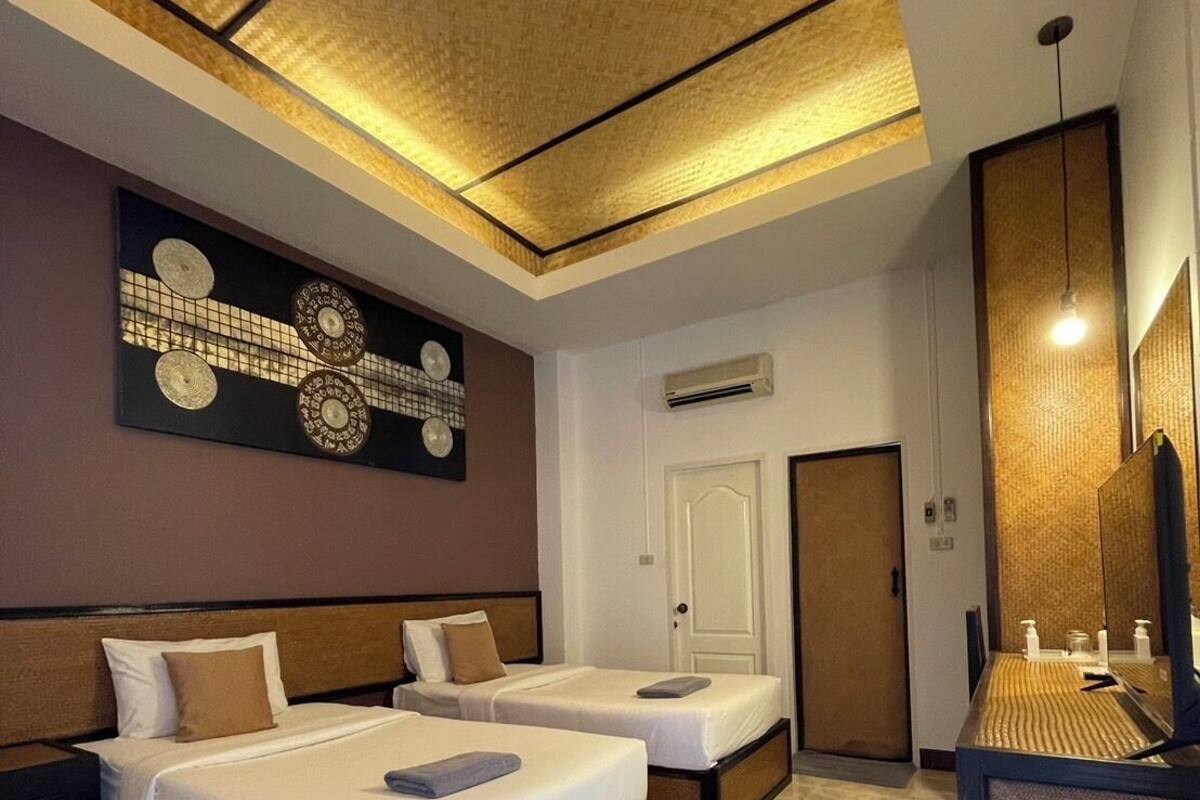 A hotel room with two beds, a large mirror, and a ceiling with a geometric pattern.