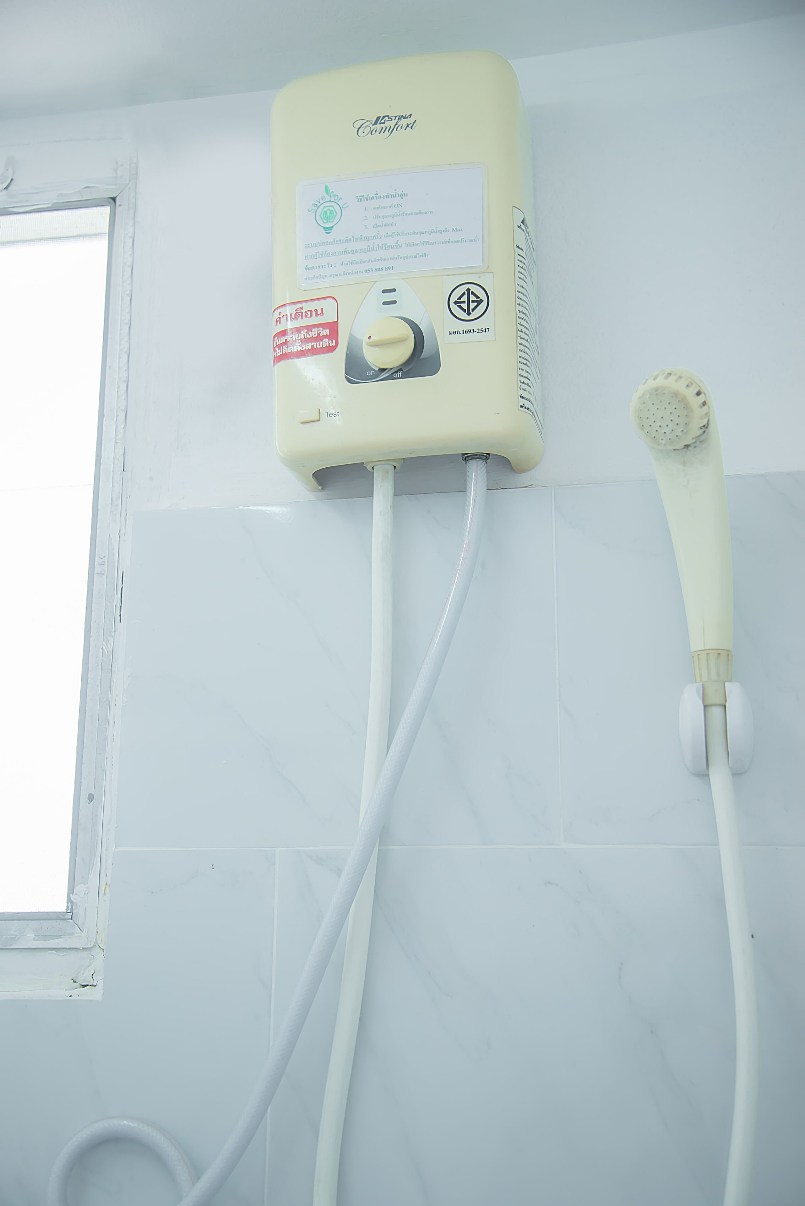 A bathroom with a wall-mounted heater and a handheld showerhead.