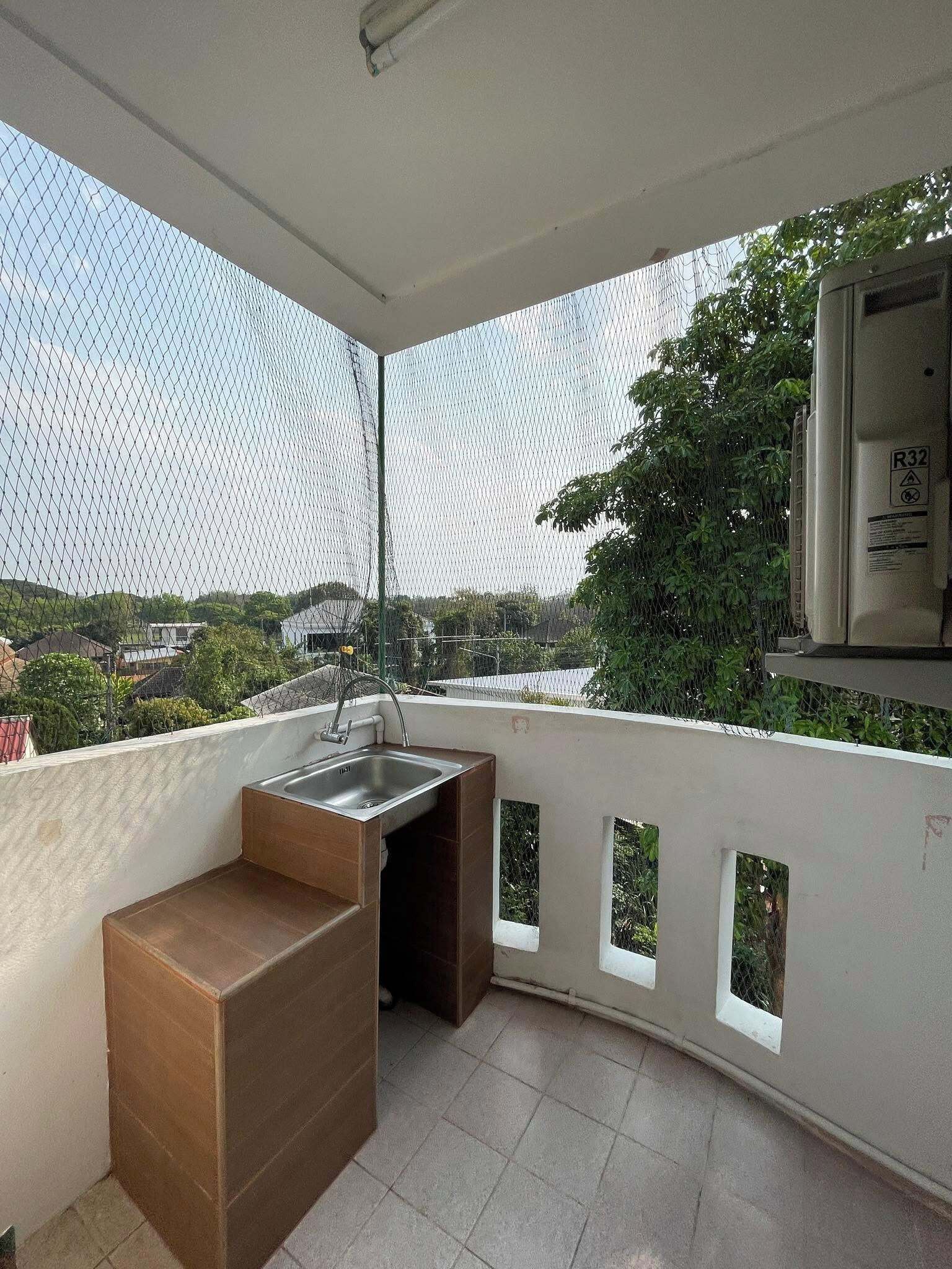 A balcony with a sink, a wooden bench, and a view of the cityscape.