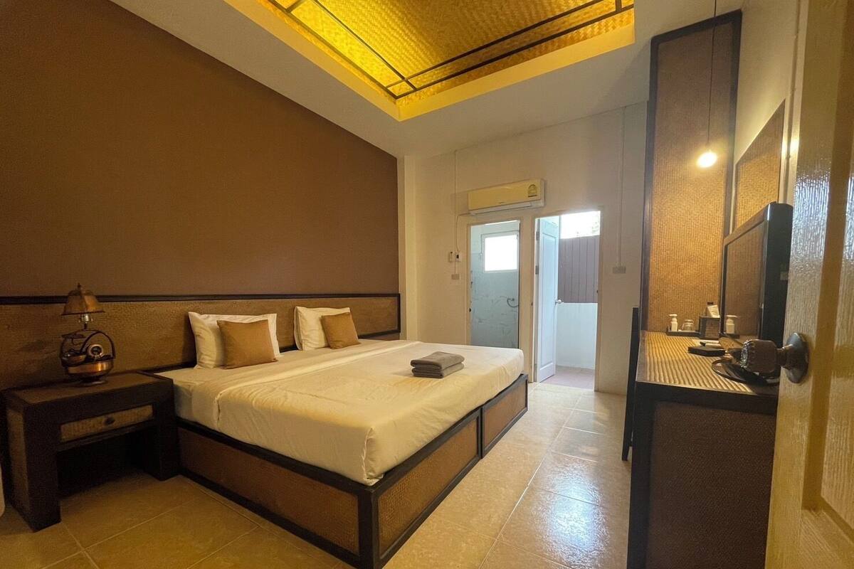 A hotel room with a bed, bedside table, lamp, and a mirror.