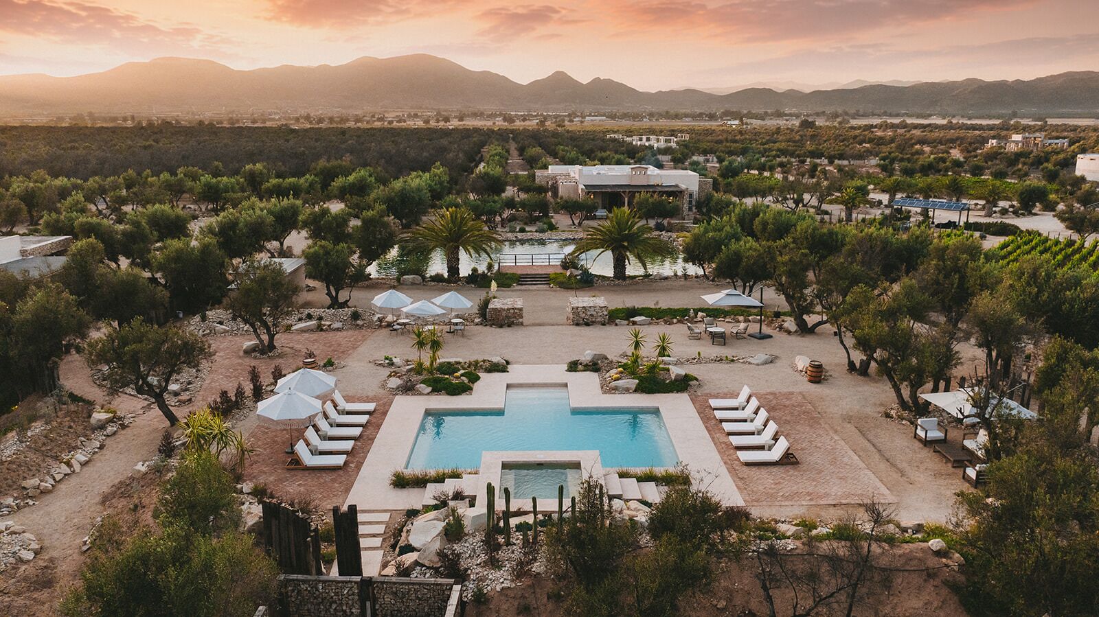 A resort with a central pool, multiple lounge areas, and a mountainous backdrop.