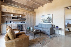 A modern living room with a sofa, coffee table, and a kitchen area with wooden cabinets and appliances. - Hábimo (Valle de Guadalupe)