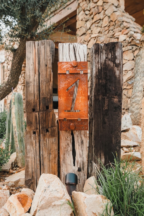 A rustic wooden gate with a metal latch, set against a backdrop of rocks and a stone wall.