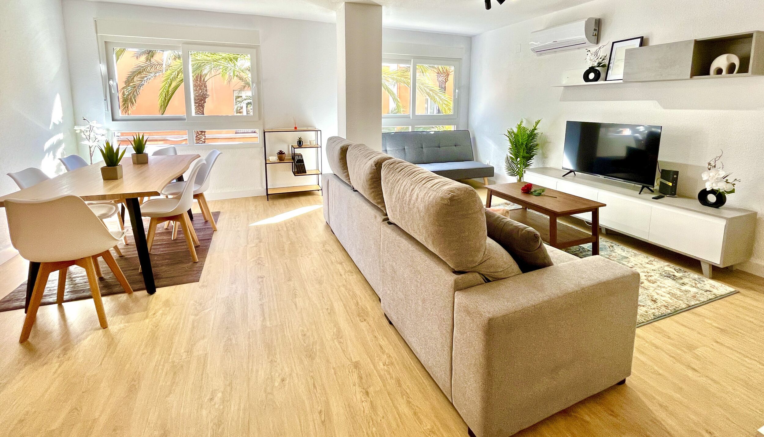 A modern living room with a sofa, TV, and dining area.