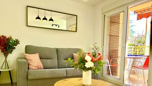 Un salon moderne avec un canapé gris, une table basse ronde en bois et un vase blanc orné de fleurs.