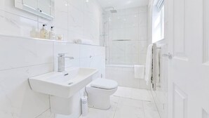 Een moderne badkamer met een wit wastafel, toilet en douche.
