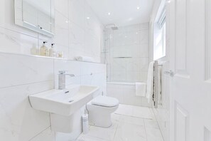A modern bathroom with a white sink, toilet, and shower area. - Spacious 1 Bed Apartment in Cheltenham w Terrace (Cheltenham)