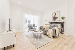 A modern living room with a sofa, coffee table, and a fireplace. - Spacious 1 Bed Apartment in Cheltenham w Terrace (Cheltenham)