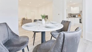 Een moderne eethoek met een ronde tafel gedekt voor vier personen, omringd door grijze fauteuils.
