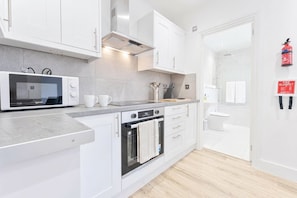 Eine moderne Küche mit weißen Schränken, einer Mikrowelle, einem Backofen und einem Spülbecken.