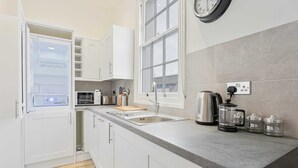 Una cucina moderna con mobili bianchi, un forno a microonde integrato, un lavandino e una macchina per il caffè.