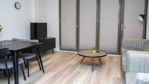 Un salon moderne comprenant une table à manger, des chaises, un canapé, un téléviseur et un placard avec une porte coulissante en verre.