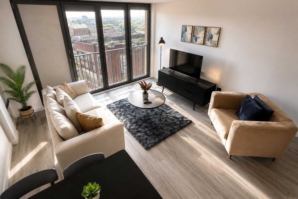 A modern living room with a sofa, armchair, coffee table, and TV.