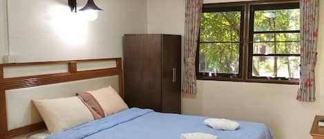 A bedroom with a bed, a nightstand, a wardrobe, a window with curtains, and a ceiling light.