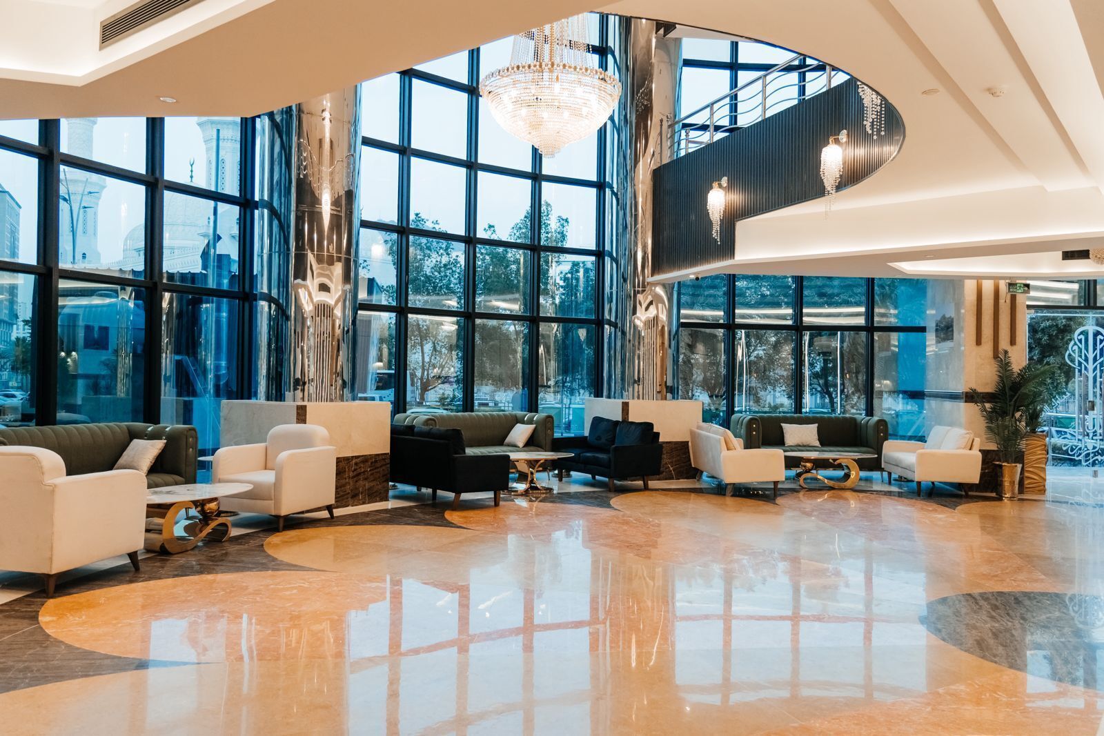Un vestíbulo amplio con ventanas grandes, muebles modernos y un candelabro central.
