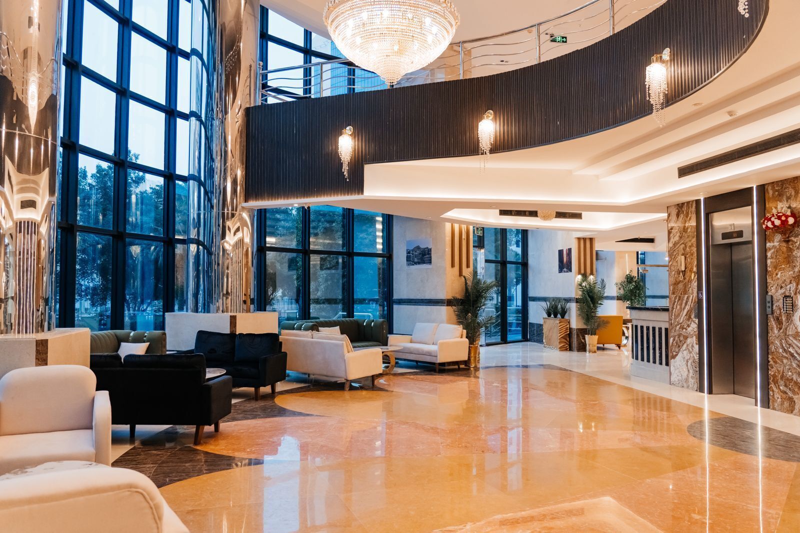 A spacious lobby with a high ceiling, large windows, and a modern chandelier.
