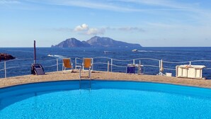 Una piscina con vista al mar y una isla rocosa.
