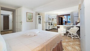 Un dormitorio con cama, escritorio y silla. Hay una puerta que da a otra habitación.