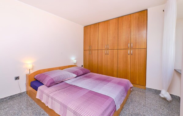Un dormitorio con una cama, un armario de madera y una mesita de noche con una lámpara.