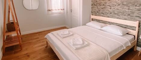 A bedroom with a wooden bed, a hanging chair, a round mirror, and a stone-patterned wall.