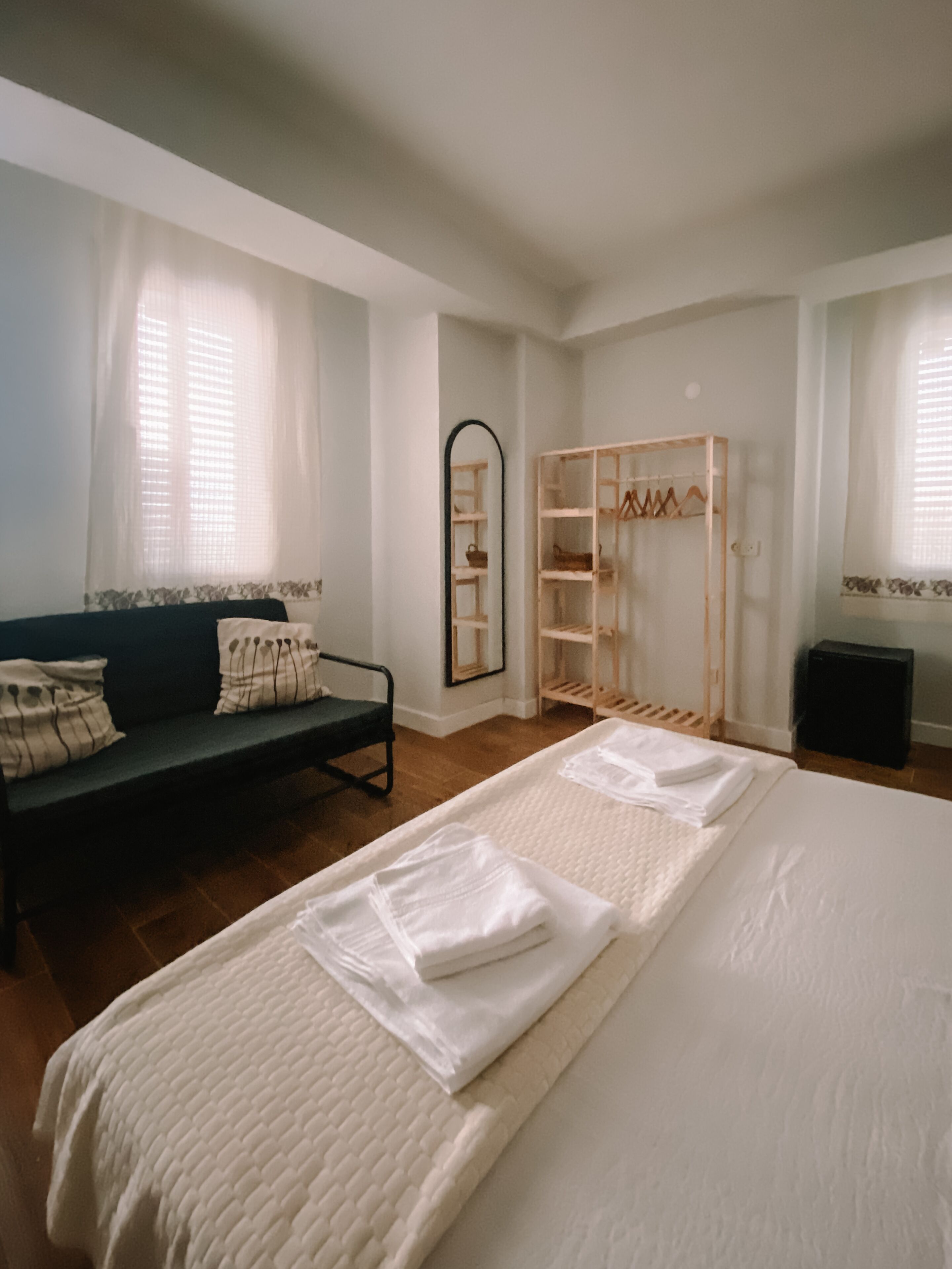 Een slaapkamer met een bed, een bankje, een kledingkast en een spiegel.