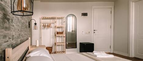 A bedroom with a large bed, a wooden nightstand, a mirror, and a wardrobe.