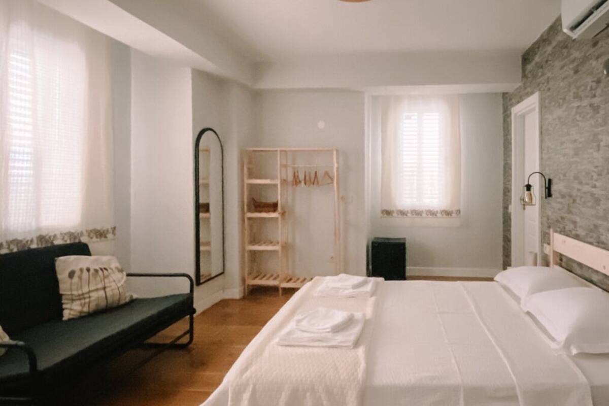 A bedroom with a wooden bed, a bench, a wardrobe, and a mirror.