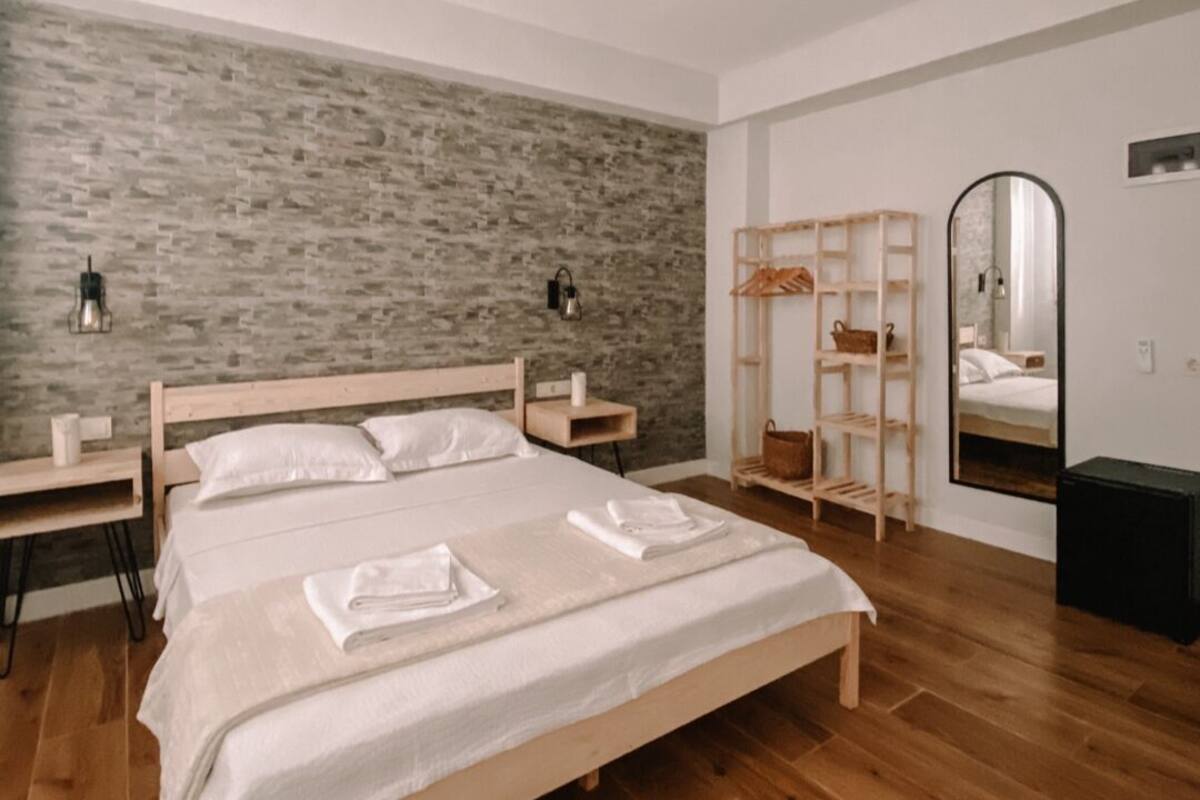 A bedroom with a wooden bed, two bedside tables, a mirror, and a wardrobe.