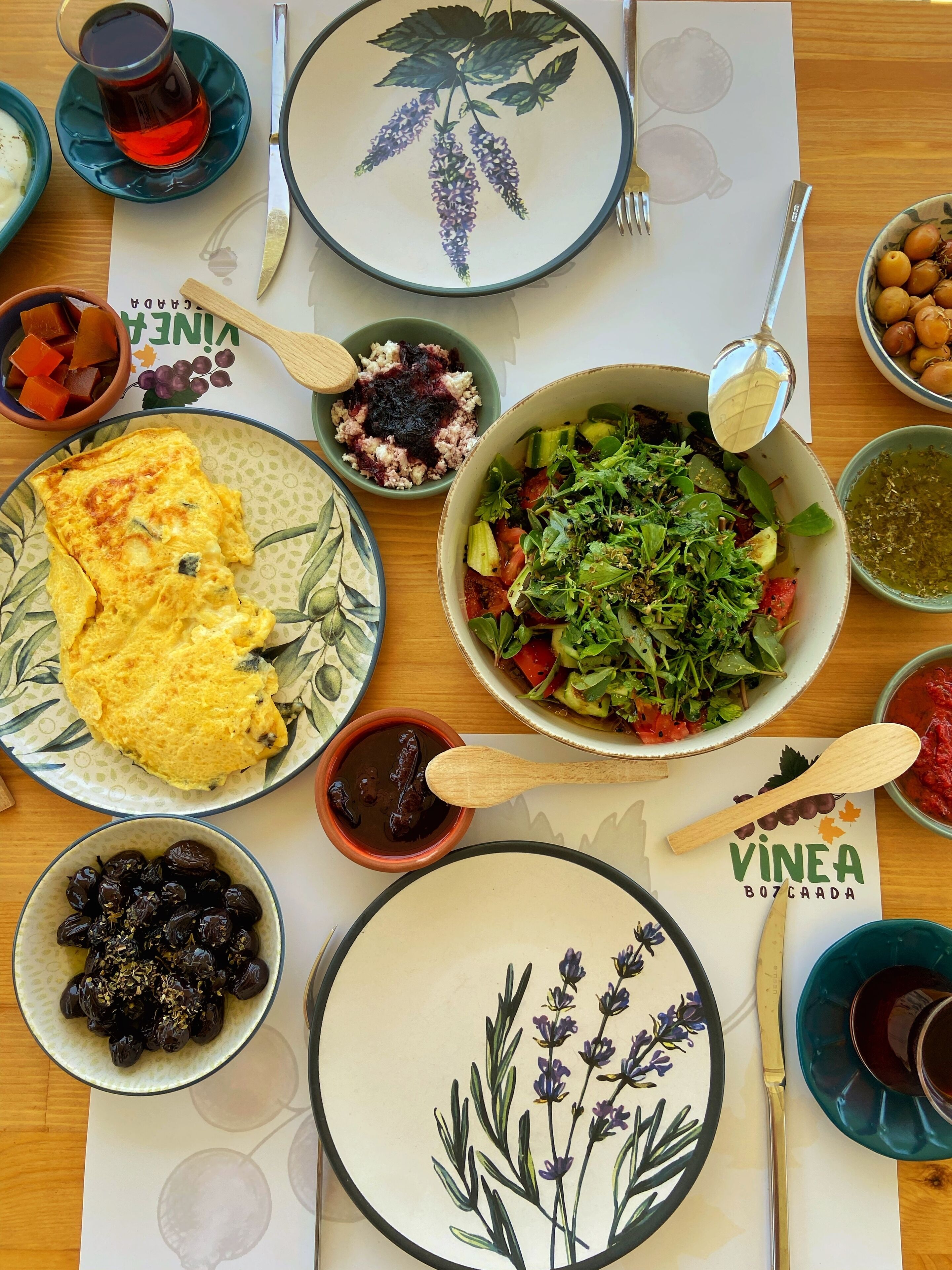 Taula amb diversos plats, com ara truita, amanida i bols de fruita i verdura.