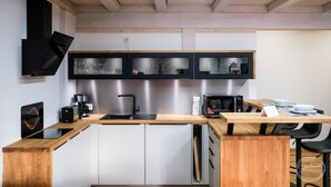 A modern kitchen with a wooden countertop, built-in appliances, and a skylight. - Gästewohnung Storchennest (Teichland)