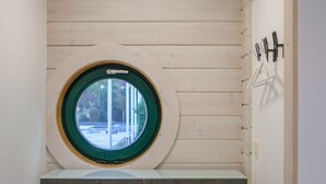 A room with a built-in circular window, a grey cabinet, and a wooden floor. - Gästewohnung Storchennest (Teichland)