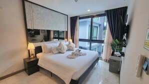 A hotel room with a large bed, a nightstand with a lamp, a flat-screen TV mounted on the wall, and a window with curtains. - B406 - 1 Bedroom Condo Pool View Near Ao Nang Beach (Krabi)
