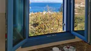 A room with a large window offering a view of the sea and hills. - Tilos Villa (Tilos)