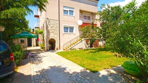 Un edificio con facciata in pietra, ingresso pavimentato e un piccolo giardino.