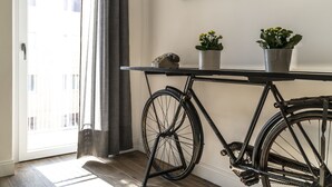 A bicycle leaning against a wall, a potted plant, and a telephone on a table. - Vintage Apartment Cipro (Rome)