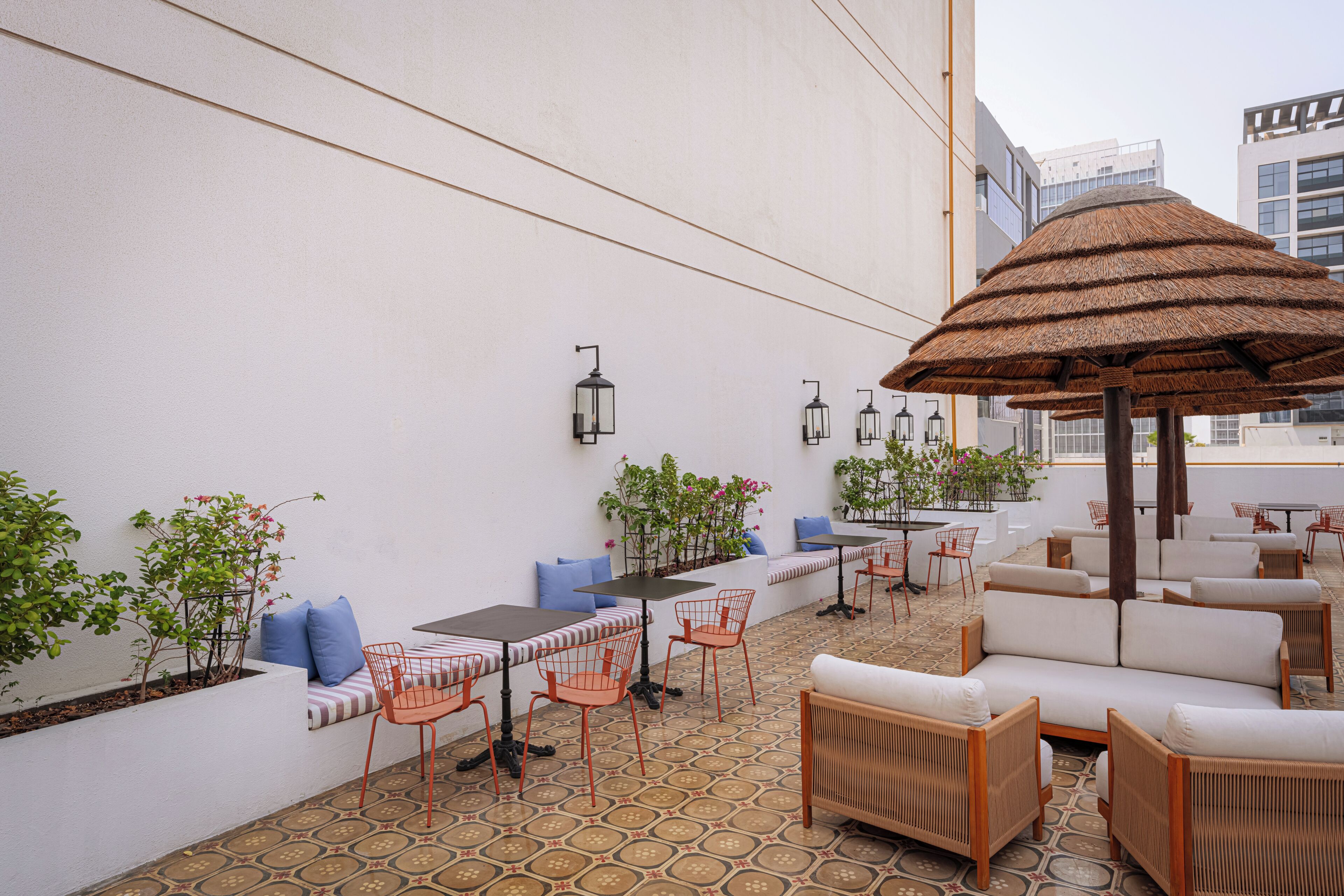 An outdoor seating area with tables, chairs, and a thatched umbrella.