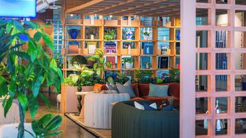 Un interior acogedor con una estantería de madera, asientos cómodos y varias plantas.