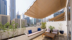 A balcony with a seating area, a table, and potted plants.