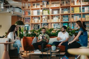 Un grupo de personas sentadas en un sofá en una habitación con una estantería llena de libros.