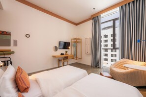 Ein Hotelzimmer mit Bett, Schreibtisch, Fernseher und Blick auf die Stadt.