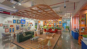 A modern interior with a central seating area, a bookshelf filled with decorative items, and framed artwork on the walls.