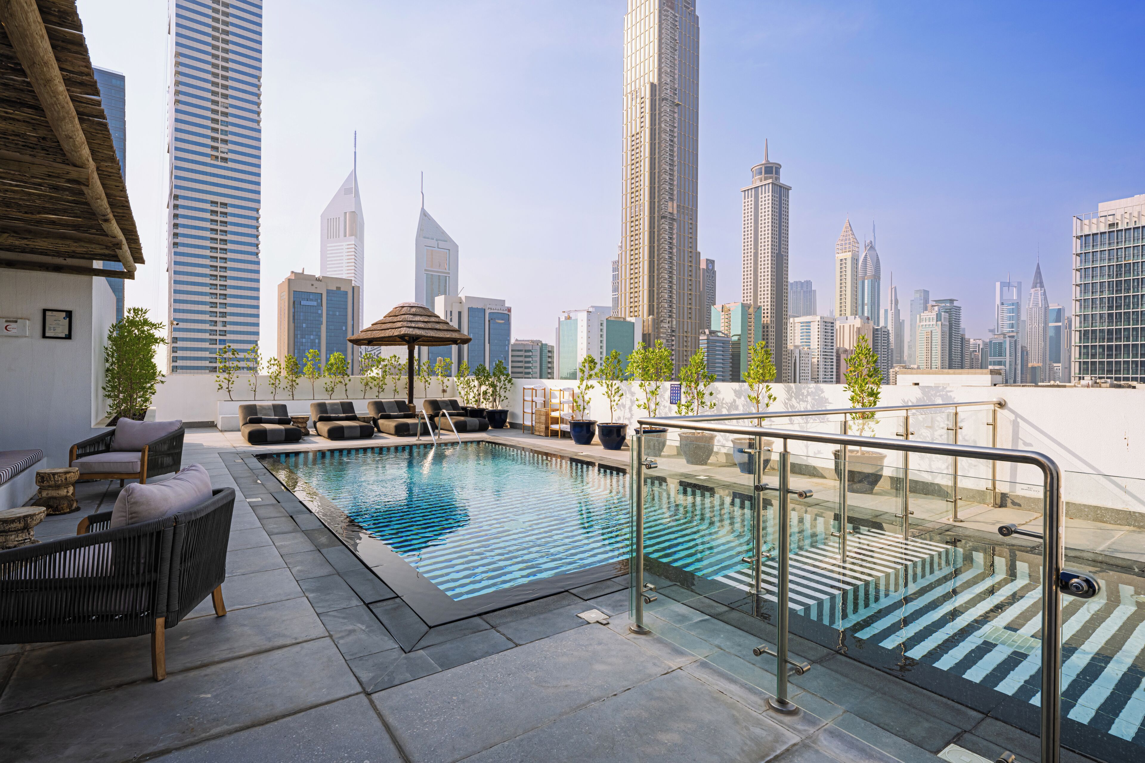 A rooftop pool with lounge chairs and a view of the city skyline.